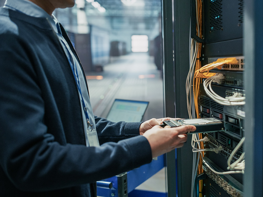 IT technician installs a server blade into a rack in a data center